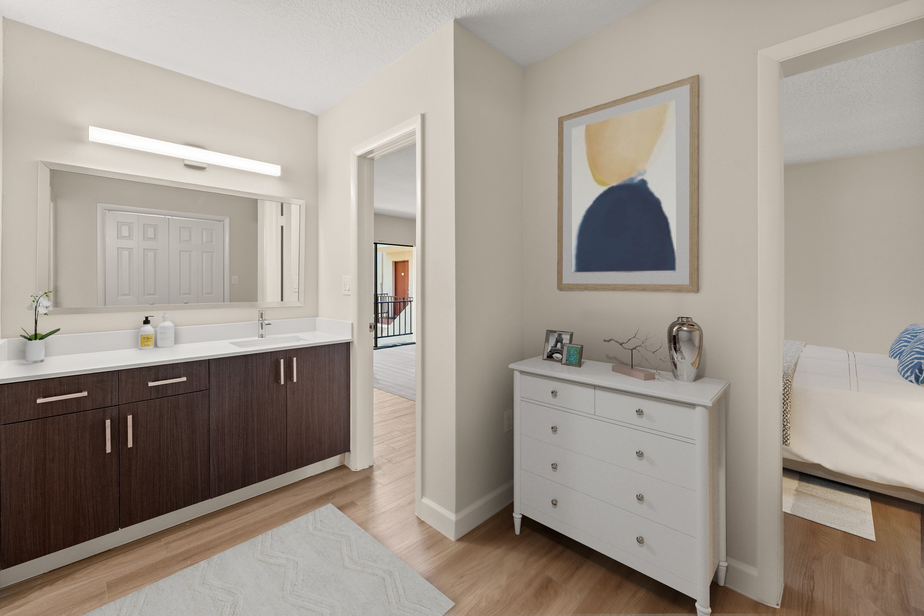 A white dresser with a blue and yellow painting above it in a room with wooden floors.